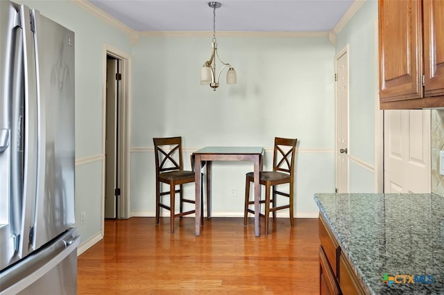 dining space featuring light hardwood / wood-style flooring, crown molding, and a chandelier