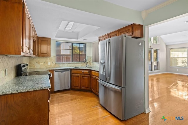 kitchen with light stone counters, light hardwood / wood-style floors, sink, and stainless steel appliances