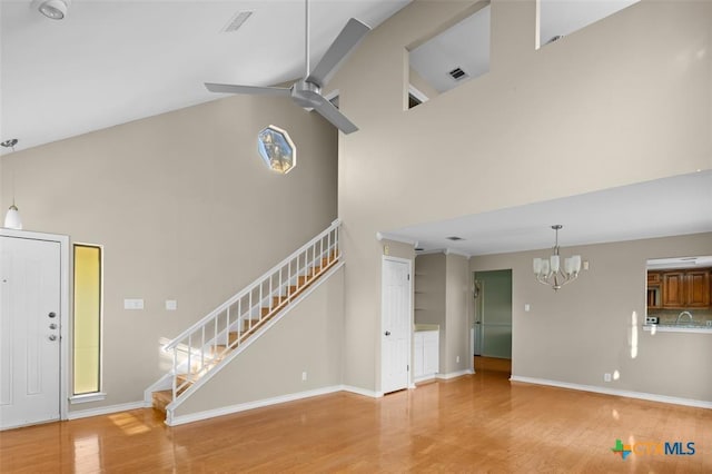 unfurnished living room with beamed ceiling, ceiling fan with notable chandelier, wood-type flooring, and high vaulted ceiling