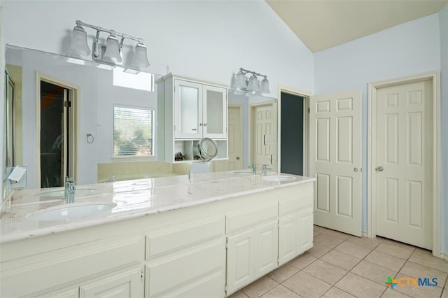 kitchen with white cabinetry, light tile patterned floors, light stone countertops, and vaulted ceiling