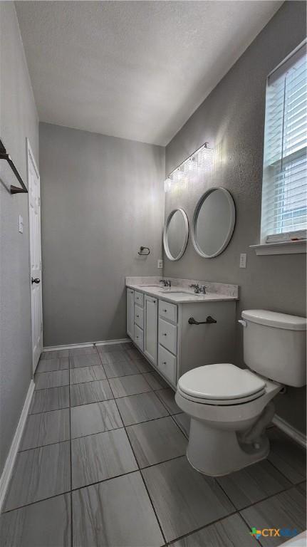9012 Lonesome Oak Dr, Temple, TX 76502 - bathroom with toilet, double vanity, baseboards, and a textured ceiling