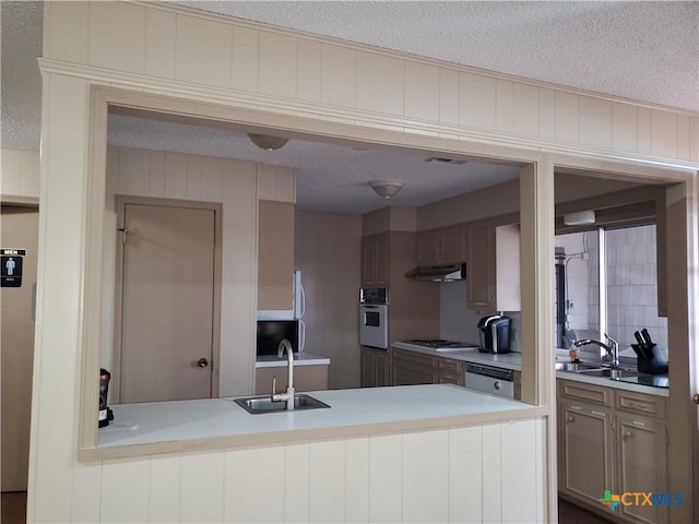 kitchen with sink, oven, a textured ceiling, and gas cooktop