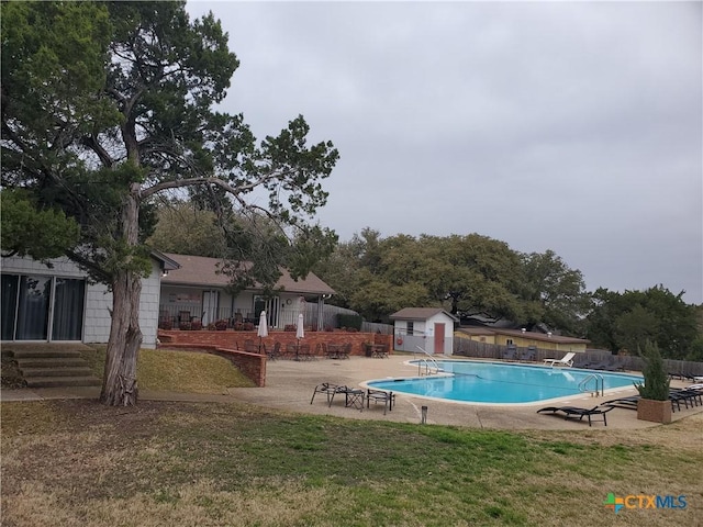 view of pool featuring a yard, a shed, and a patio