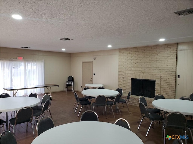 dining area featuring dark wood-type flooring, a textured ceiling, and a fireplace