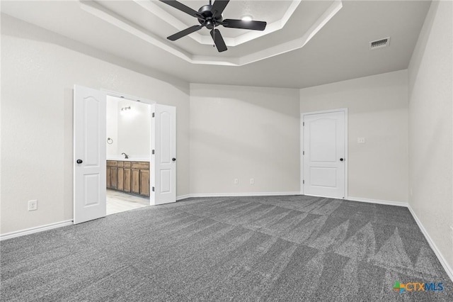 carpeted spare room featuring a raised ceiling and ceiling fan