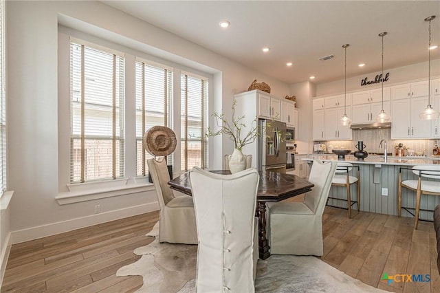 dining space with sink and light hardwood / wood-style flooring