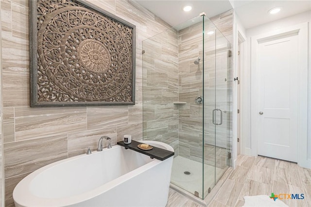 bathroom featuring tile walls and separate shower and tub