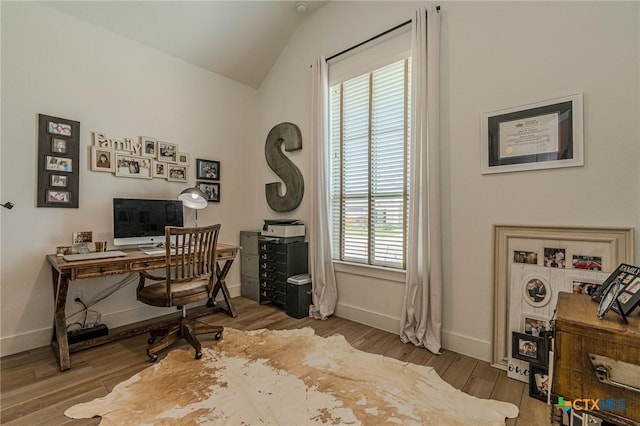 home office featuring lofted ceiling, a healthy amount of sunlight, and hardwood / wood-style floors