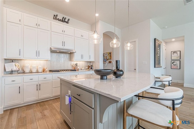 kitchen featuring pendant lighting, a center island, decorative backsplash, and white cabinets