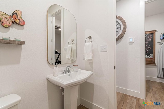 bathroom featuring hardwood / wood-style flooring and toilet