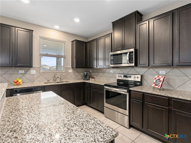 kitchen with light stone counters, appliances with stainless steel finishes, and sink