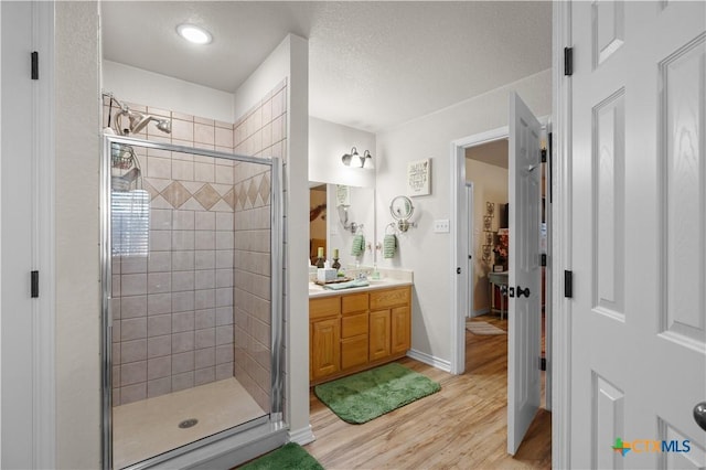 bathroom with vanity, wood-type flooring, and a shower with door