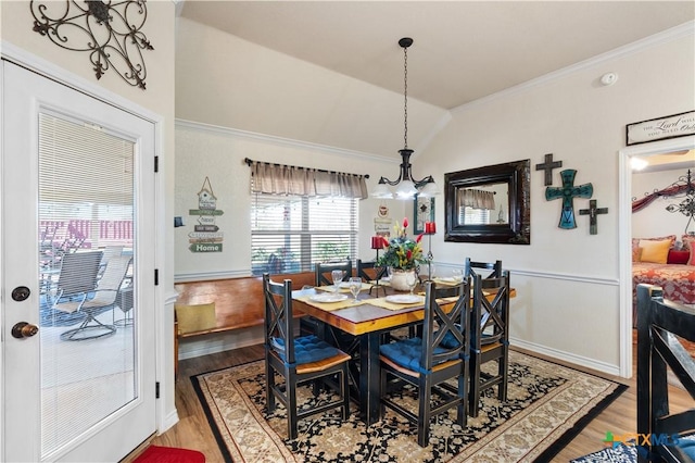 dining space with hardwood / wood-style floors, a notable chandelier, crown molding, and vaulted ceiling