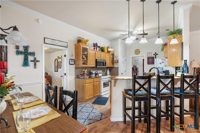 kitchen featuring a kitchen bar, backsplash, white appliances, ceiling fan, and pendant lighting