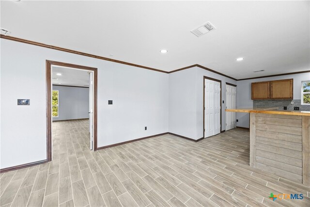 kitchen featuring a breakfast bar area, decorative backsplash, crown molding, and light hardwood / wood-style flooring