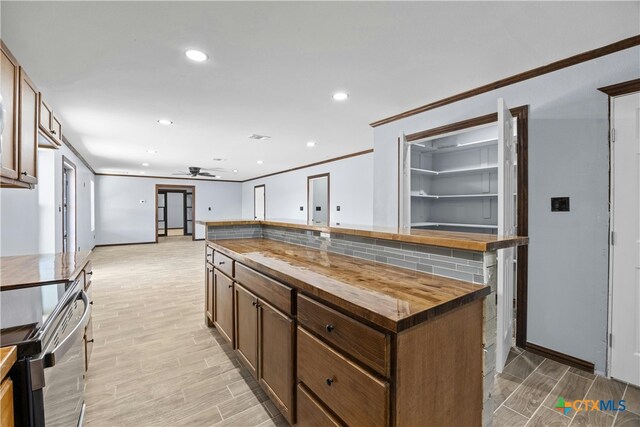 kitchen with a center island, stainless steel range with electric stovetop, butcher block countertops, backsplash, and light hardwood / wood-style flooring