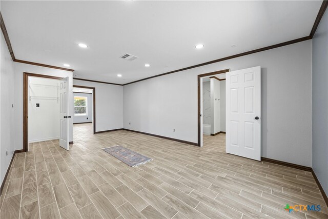 empty room featuring light wood-type flooring and crown molding