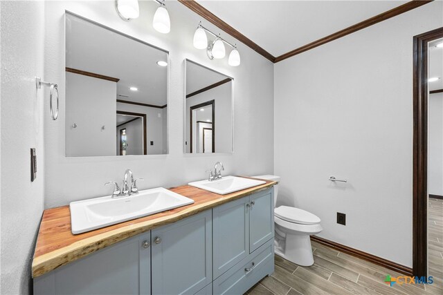 bathroom with wood-type flooring, vanity, toilet, and ornamental molding