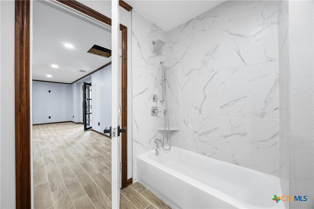 bathroom with tiled shower / bath combo and crown molding