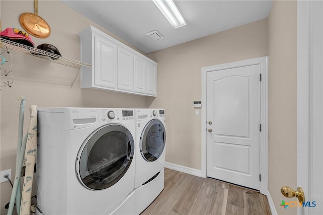 washroom featuring washing machine and dryer, cabinet space, light wood-style floors, and baseboards