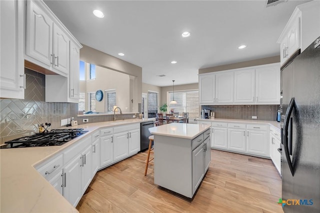 kitchen with white cabinetry, black appliances, a kitchen island, and a sink