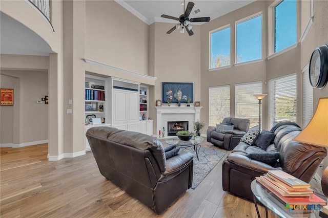 living area with light wood-type flooring, baseboards, ornamental molding, and a fireplace