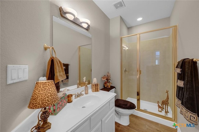 bathroom with visible vents, a shower stall, vanity, and toilet