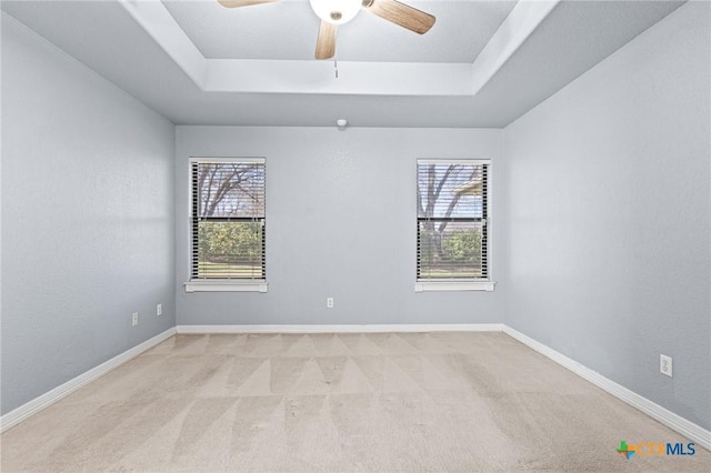 unfurnished room with a raised ceiling, a wealth of natural light, and baseboards