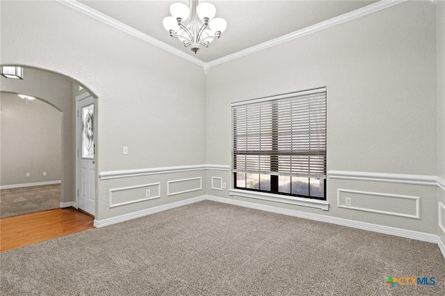 unfurnished room with arched walkways, a wainscoted wall, carpet floors, crown molding, and an inviting chandelier