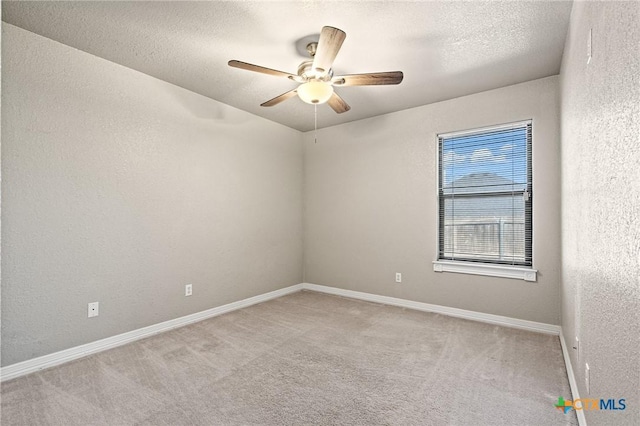 unfurnished room with light colored carpet, a textured wall, a ceiling fan, a textured ceiling, and baseboards