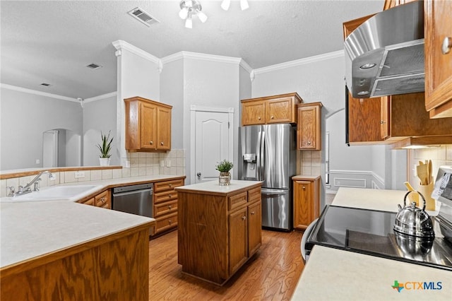 kitchen featuring stainless steel appliances, visible vents, backsplash, a sink, and wall chimney exhaust hood