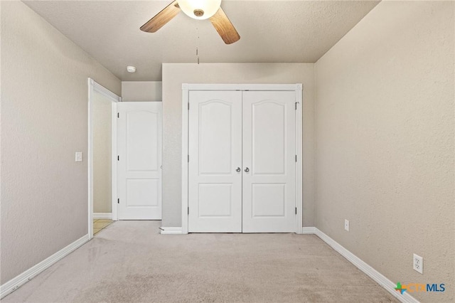 unfurnished bedroom with baseboards, a closet, a ceiling fan, and light colored carpet