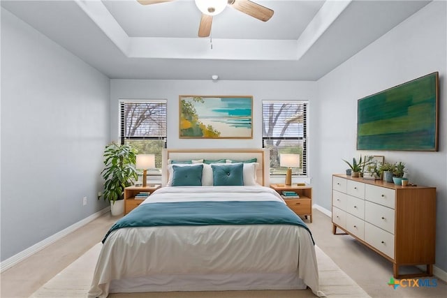 bedroom featuring light carpet, multiple windows, and a tray ceiling