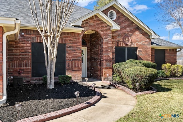 view of front of house featuring brick siding and a shingled roof