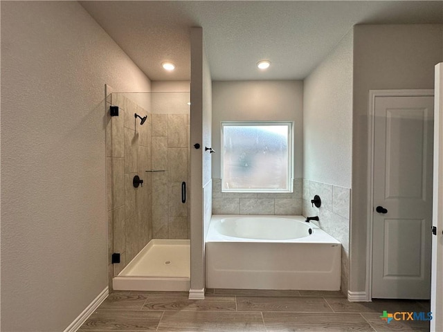 3104 Gryffindor Ln, Killeen, TX 76549 - bathroom featuring a bath, a shower stall, wood tiled floors, a textured ceiling, and a textured wall