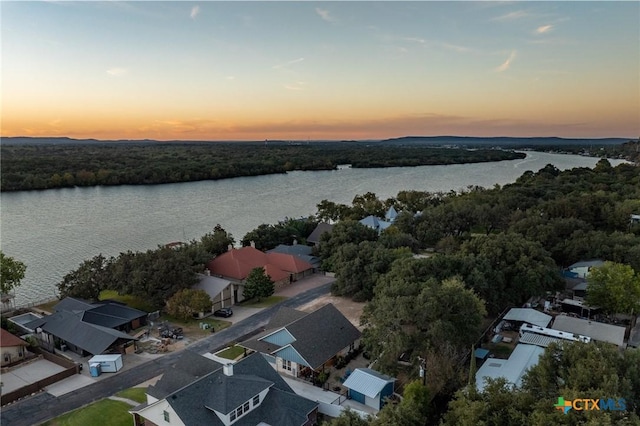 aerial view at dusk featuring a water view