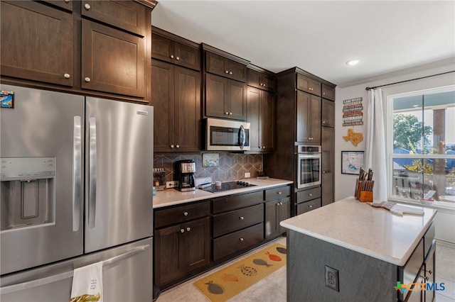 kitchen with stainless steel appliances, light tile patterned floors, decorative backsplash, dark brown cabinets, and a kitchen island