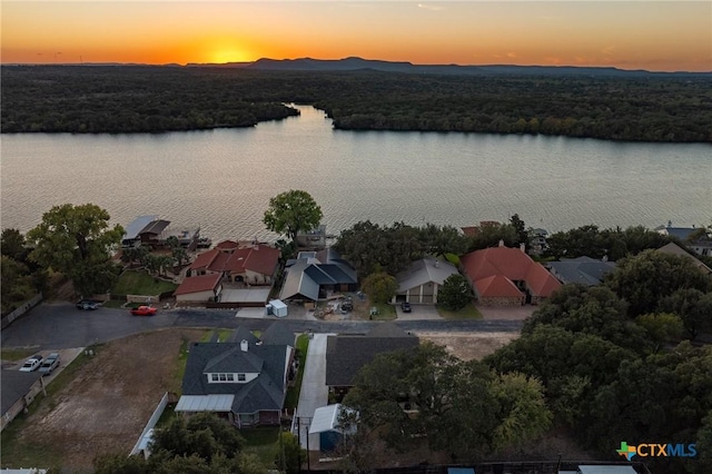 aerial view at dusk featuring a water view