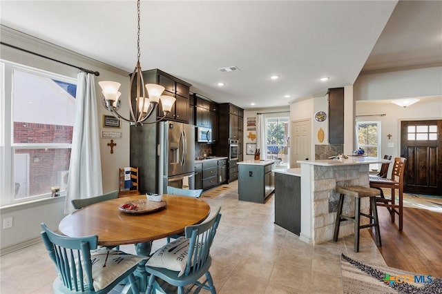 dining area with light wood-type flooring, an inviting chandelier, and crown molding