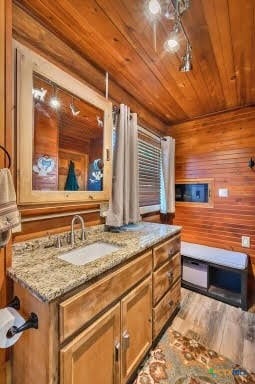 bathroom with wood walls, wooden ceiling, wood-type flooring, and sink