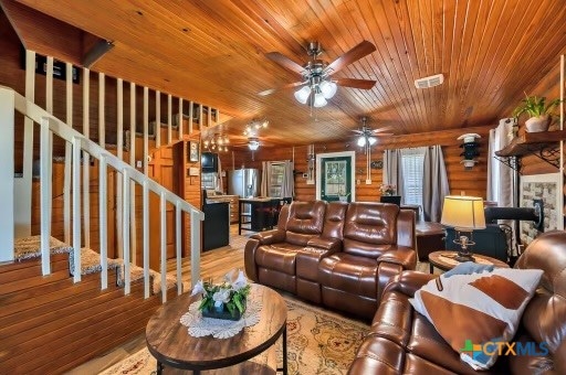 living room featuring wood walls, wooden ceiling, ceiling fan, and light hardwood / wood-style flooring