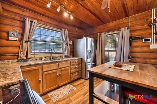 kitchen featuring light hardwood / wood-style flooring, log walls, wood ceiling, and stainless steel fridge