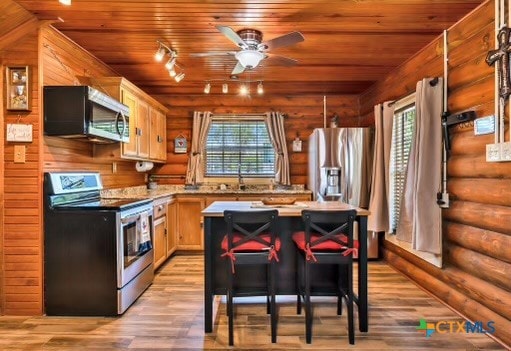 kitchen with stainless steel appliances, a healthy amount of sunlight, wood ceiling, and light hardwood / wood-style flooring