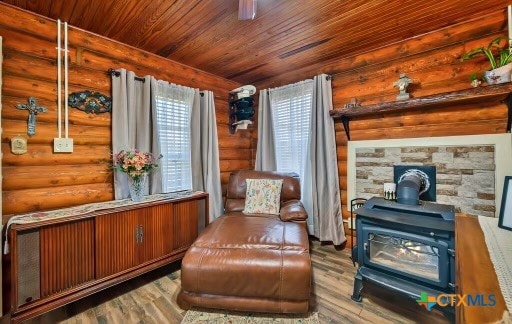 sitting room with hardwood / wood-style flooring, a wood stove, and log walls