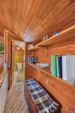 interior space with wood walls, wood ceiling, carpet flooring, and lofted ceiling