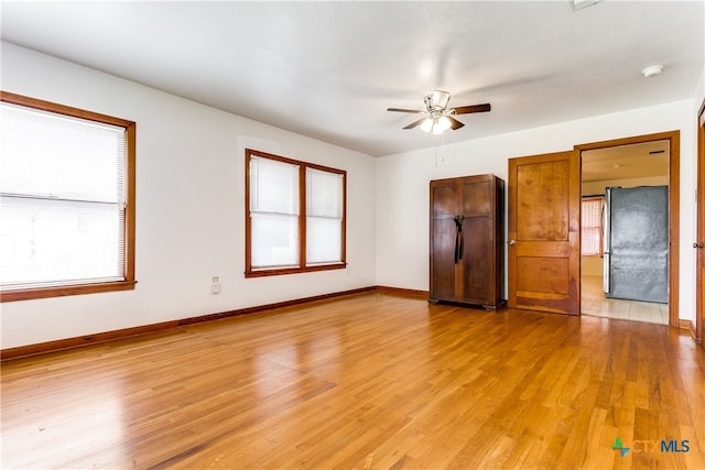 spare room with ceiling fan, a healthy amount of sunlight, and light hardwood / wood-style flooring