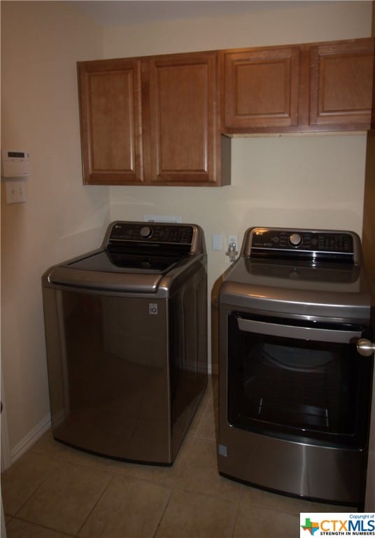 2005 Granite Springs Rd, Leander, TX 78641 - laundry area featuring cabinet space, washing machine and clothes dryer, light tile patterned flooring, and baseboards