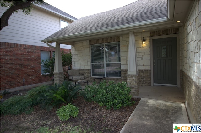 2005 Granite Springs Rd, Leander, TX 78641 - view of exterior entry with a shingled roof, a porch, brick siding, and stone siding