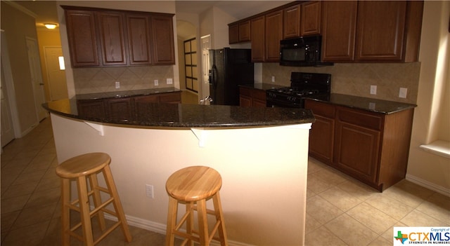 kitchen featuring backsplash, a kitchen bar, black appliances, and a center island