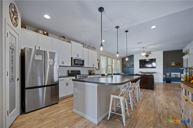 2023 Chilton Hall, San Antonio, TX 78253 - kitchen featuring dark countertops, a sink, white cabinetry, light wood-style flooring, and appliances with stainless steel finishes